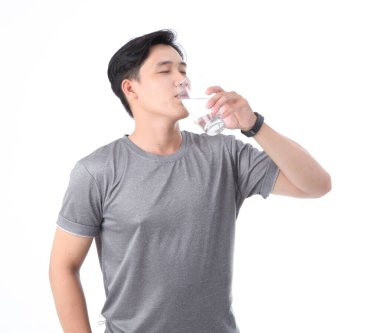 Asyalı yakışıklı ve neşeli genç adam bir bardak içme suyuyla, arka planda izole edilmiş.