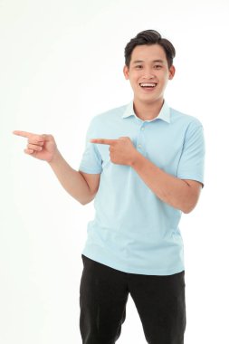 Asyalı yakışıklı ve neşeli genç adam işaret ediyor ve arka planda izole edilmiş el hareketini gösteriyor.