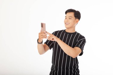 Asyalı yakışıklı ve neşeli genç adam, beyaz arka planda izole edilmiş akıllı bir telefon tut.