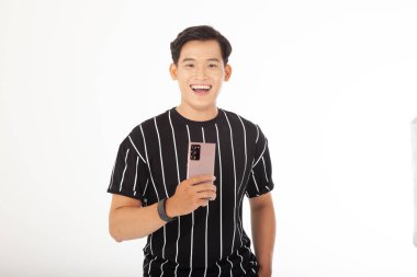 Asyalı yakışıklı ve neşeli genç adam, beyaz arka planda izole edilmiş akıllı bir telefon tut.