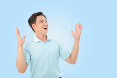 Stüdyoda açık mavi arka planda mutlu genç bir adamın yatay portresi