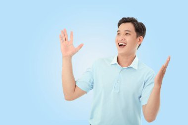 Stüdyoda açık mavi arka planda mutlu genç bir adamın yatay portresi