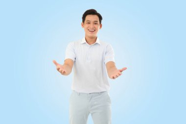 Stüdyoda açık mavi arka planda mutlu genç bir adamın yatay portresi