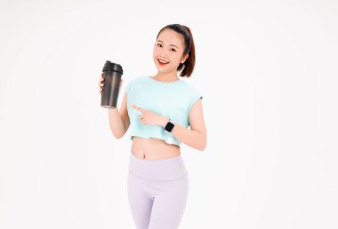 Asyalı genç, güzel ve neşeli bir kadının portresi. Elinde sallama şişesi, arka planda izole edilmiş.