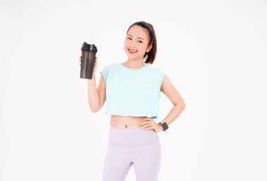 Asyalı genç, güzel ve neşeli bir kadının portresi. Elinde sallama şişesi, arka planda izole edilmiş.