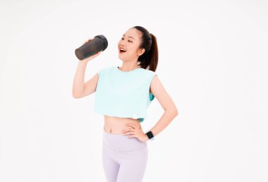 Asyalı genç, güzel ve neşeli bir kadının portresi. Elinde sallama şişesi, arka planda izole edilmiş.