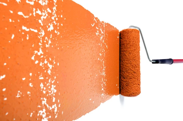 Rodillo con pintura naranja en la pared blanca — Foto de Stock