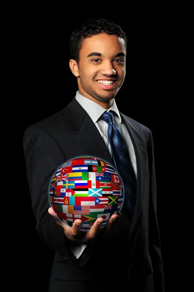 Empresario sosteniendo esfera con banderas del mundo — Foto de Stock