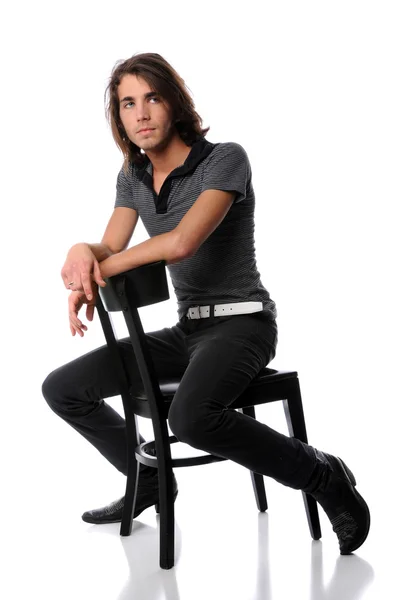 Genç adam siyah sandalye sittin — Stok fotoğraf