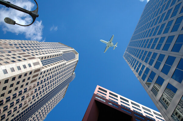 Corporate jet flying high above business district.