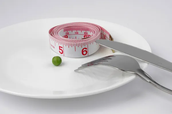 Pea and measuring tape on a plate — Stock Photo, Image