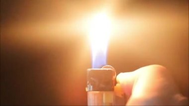 Gaz lambası videoları. Karanlıkta elinde yanan çakmağın siyah arka planında yakın çekim ateşi. Gaz çakmağı olan bir adam..