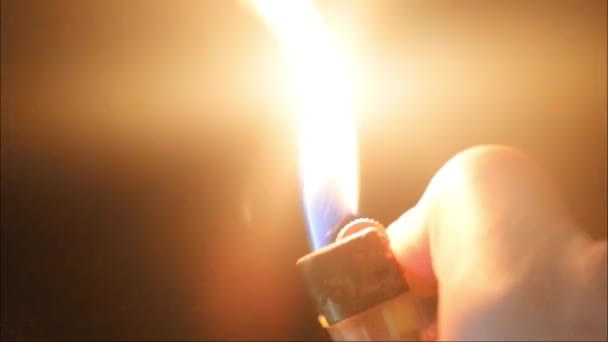 ガスライタービデオ 黒の背景の闇の中の手の中のライターの点火からのクローズアップ火災 ガスライターを持った男の手 — ストック動画