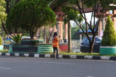 Bir kadın hademe, Muara Bungo, Jambi, 25 Mayıs 2022 'de bir otobanda çöp temizliyor.