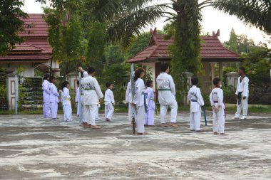 skilled teenagers in white uniforms simultaneously perform a series of taekwondo exercises with special breathing. Taekwondo practice at the city park of Muara Bungo, Jambi, May 23, Indonesia.