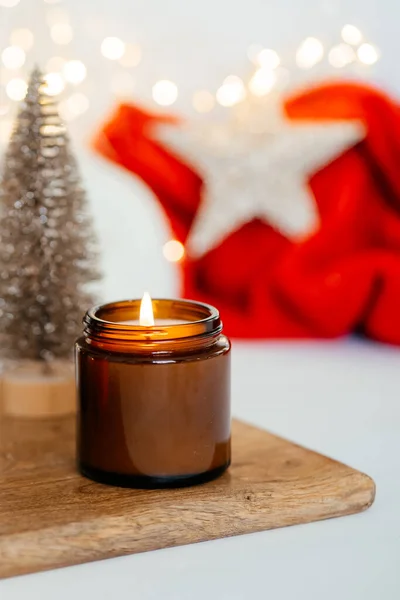 burning natural soy scented candle on the background of Christmas decorations