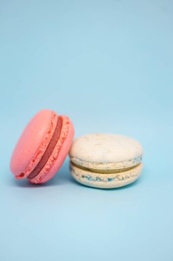 Mavi arka planda pembe ve mavi makaronlar. Lezzetli taze tatlı. Tek renk olsun. Yılın rengi.