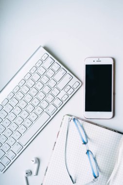 Ofis işleri için aletler. Arkaplanda klavye, telefon, not defteri ve gözlük.