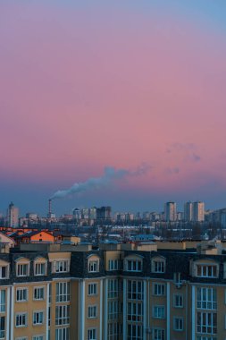 Şafak vakti şehir manzarası. Mavi duman bacadan çıkıyor. pembe gökyüzü 