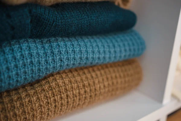 Beyaz raflarda farklı renklerde örülmüş bir sürü şey var. Yüksek kalite fotoğraf