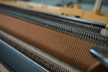 Bir örgü makinesine sıcak karamel bej örülmüş kumaş. Örgü makinesinde bir şeyler yapma süreci. İş olarak örgü örüyorum. Yüksek kalite fotoğraf