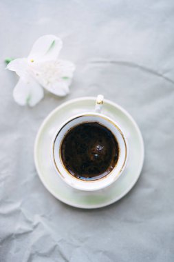 cup of coffee and white flower on gray background. top view . High quality photo