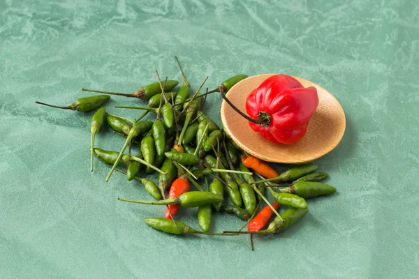 Pimienta roja con pequeños pimientos verdes alrededor — Foto de Stock