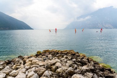 Riva del Garda, İtalya - 22 Eylül 2021: Sporcular göl kenarındaki bir sörf akademisinde rüzgar sörfü pratiği yapıyorlar.
