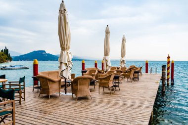 Yağmur, İtalyan gölünde turistler için müşterisi olmayan bir restoranın masa ve sandalyelerini ıslatıyor..