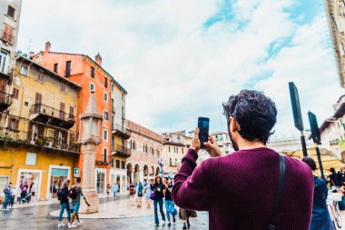 Verona, İtalya - 20 Eylül 2021: Verona Meydanı 'ndaki genç bir turist cep telefonuyla fotoğraf çekip sosyal ağlardaki arkadaşlarına gönderdi.