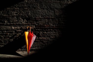 Şemsiye güneşli bir günde terk edilir ve duvara yaslanır..