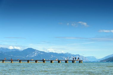 Sirmione 'deki panoramik, arka planda dağlarla birlikte Lago di Garda' dan huzurlu bir manzara..