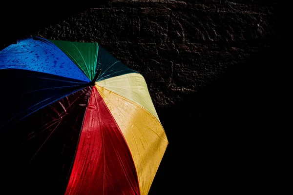 在明亮的色彩和深色的背景下 打开遮阳伞 挡住强烈的阳光 — 图库照片