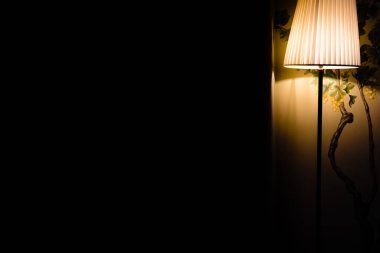 Gecenin karanlığında bir lamba bir odanın içindeki bir köşeyi aydınlatır..