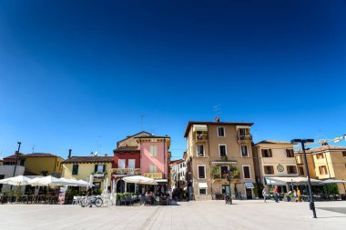 Peschiera di Garda, İtalya - 22 Ekim 2021: Güneşli bir günde restoranları olan modern şehir meydanı.
