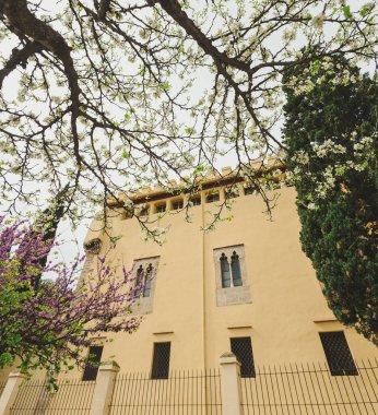 İnzivaya çekilmiş modern bir manastırın cephesinde çitler çiçek açmış güzel ağaçlar arasında görülür..