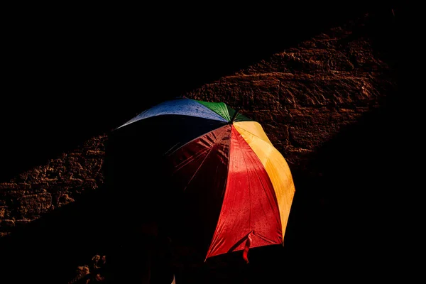 在明亮的色彩和深色的背景下 打开遮阳伞 挡住强烈的阳光 — 图库照片