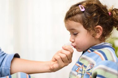 Üç yaşındaki bir kız tükürük test tüpüne tükürüp kovid19 antijen veriyor..