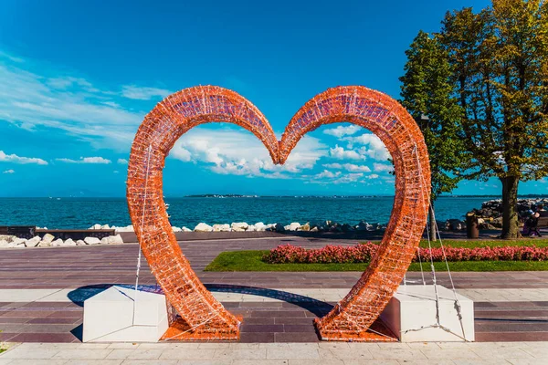 Göl kenarındaki aşıkların fotoğrafları için kalp şeklinde modern kemer..