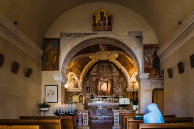 Verona, İtalya - 20 Eylül 2021: Beyazlı kadın bir rahibe İtalyan inzivasında bir bankta oturmuş dua ediyor.