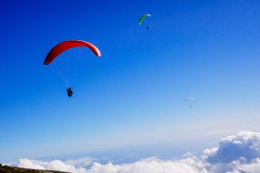 Atletler bulutların üzerinde uçmak için çok hafif bir planör, paraglider kullanırlar..