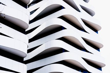 Basit çizgilerden oluşan terasları ve çağdaş mimariyle tek renkli tasarımı olan modern bir bina.