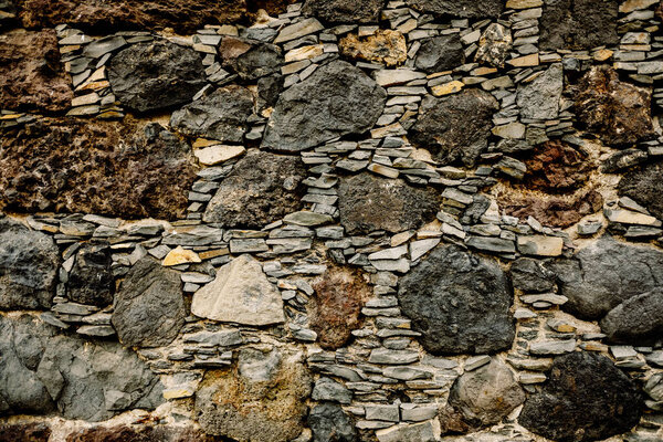 Wide stone wall secured with pebbles, rural background of craft construction.