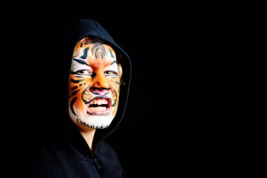 Siyah arka planda izole edilmiş, kaplan yüzlü, garip ve korkunç bir jesti olan bir çocuğun portresi..