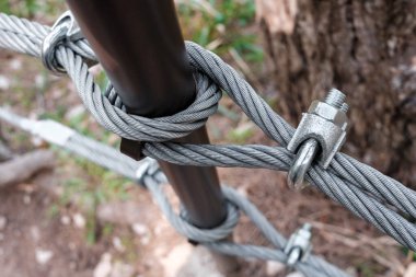 Interlocking steel cable secures a barrier on a mountain path.