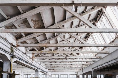 Geniş bir fabrikada beyaz kirişli ahşap bir çatı..