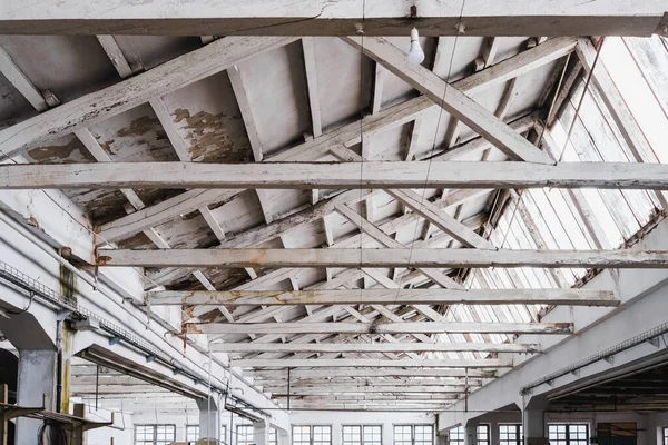 Geniş bir fabrikada beyaz kirişli ahşap bir çatı..