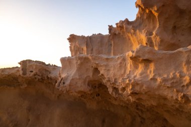 Rüzgarla aşınmış kumlu bir arazinin detayları ve kıyıya yakın dalgalar..