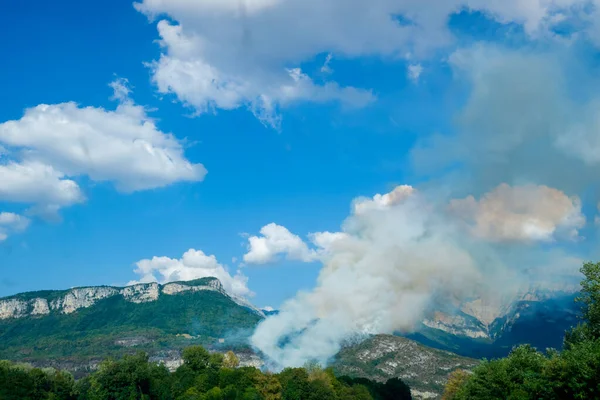 Smoke from a forest fire on a mountainside in Voreppe, France during summer day.