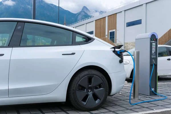 Geneva, Switzerland - August 25, 2022: A Tesla electric vehicle is recharged in a supermarket car park, free charging.